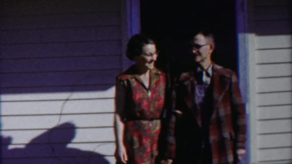 In 1958 Cheyenne County, Kansas footage, an adult couple stands at a white-sided house doorway in bright sun.