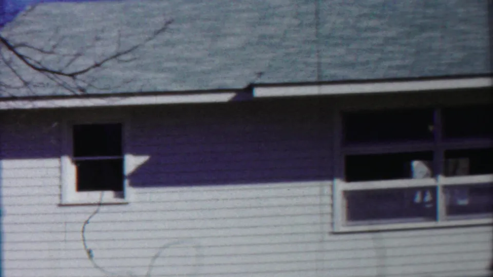 The final frame shows the Kansas house exterior without clear people, emphasizing siding, windows, roof, and a branch shadow.