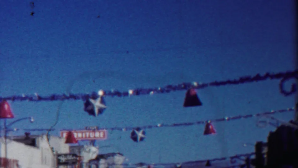 1958 Cheyenne County, Kansas frame with red bell and white star street decorations suspended above storefronts and a partial furniture sign.