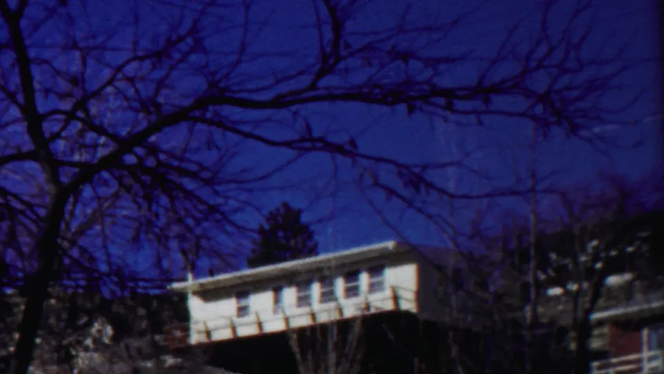 1958 Cheyenne County frame showing a white house at left, bare tree silhouettes, and winter light across the scene.