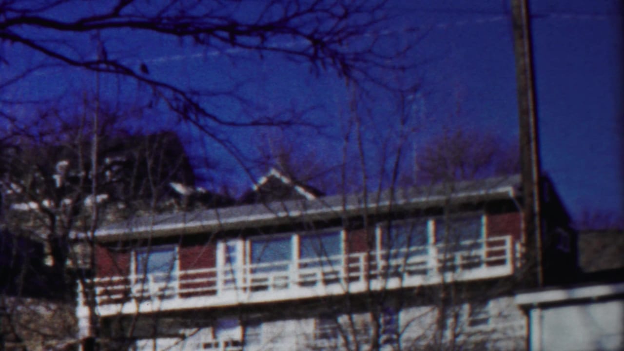 Final 1958 8mm frame of the Kansas apartment building with red siding or brick, white railings, and leafless trees.