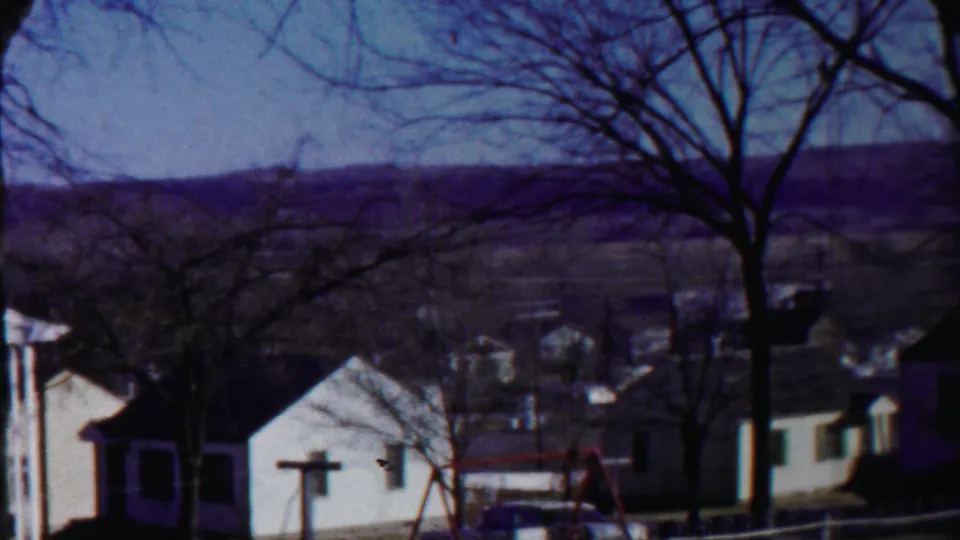 1958 Cheyenne County, Kansas view across modest homes and leafless trees toward rolling hills in the distance.