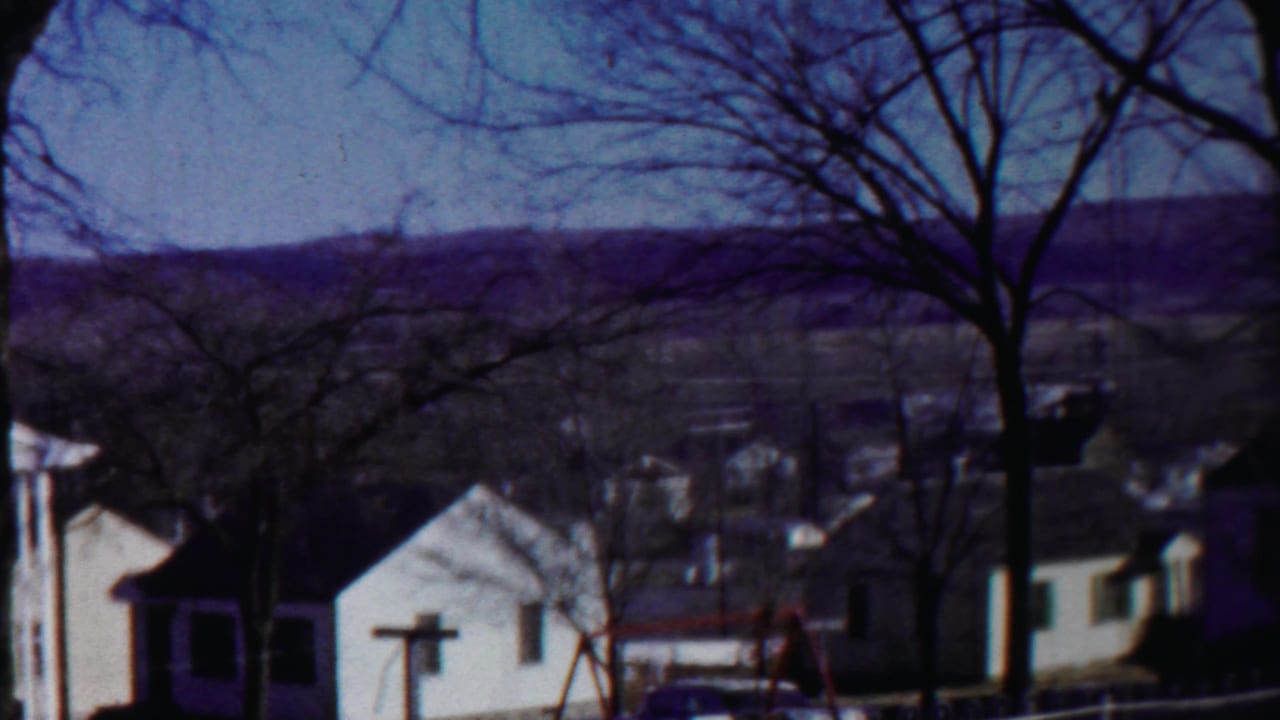 1958 Cheyenne County, Kansas frame showing residential homes, a swing set, leafless trees, and low hills beyond town.