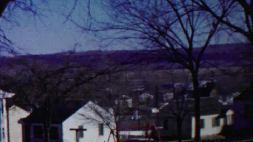 1958 8mm view of a quiet Cheyenne County, Kansas residential area with modest houses, leafless trees, and distant hills.