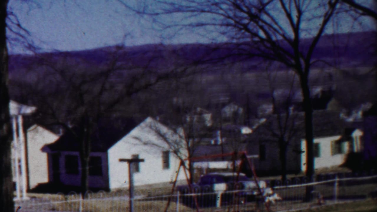 Cheyenne County, Kansas residential view with white-sided homes, bare trees, a swing set, fence line, and muted 8mm color.
