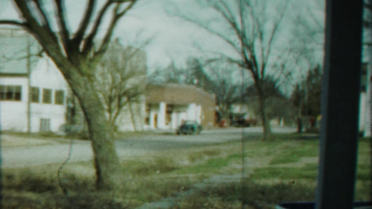 Wide roadside view with bare trees, low buildings, and a small-town street.