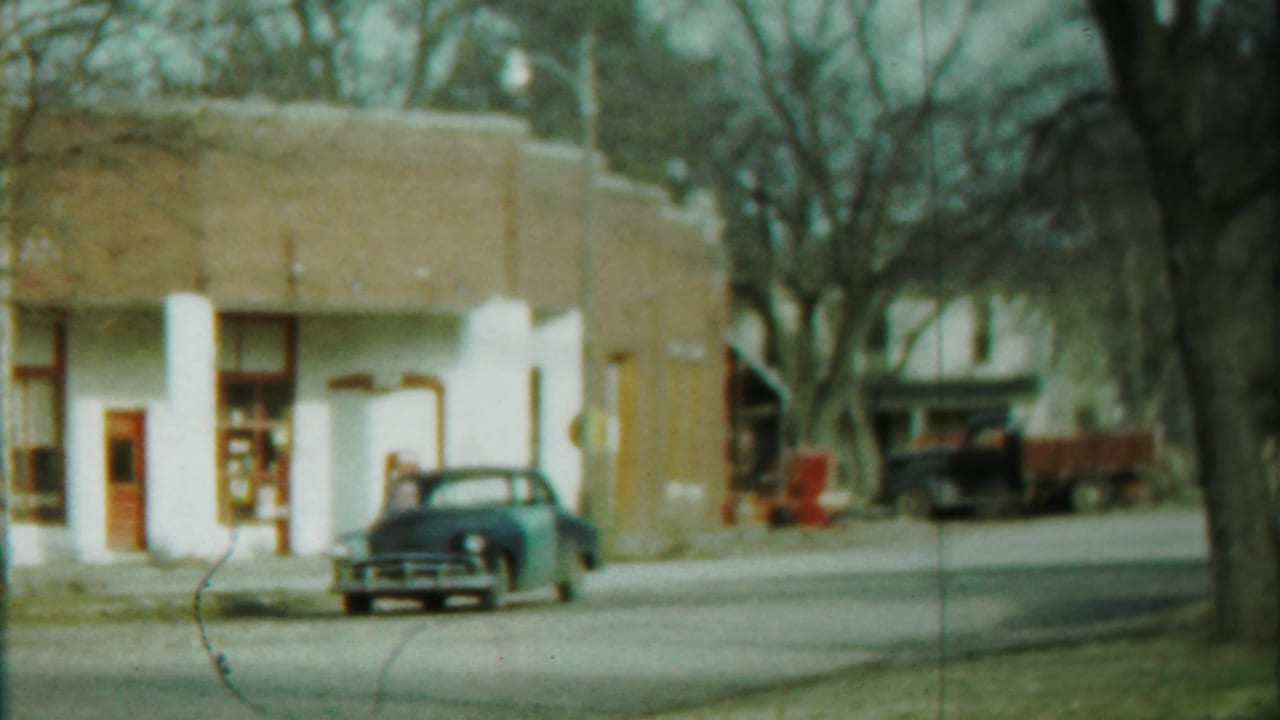 Cheyenne County, Kansas street view with a parked dark sedan, low building facade, and background pickup truck.