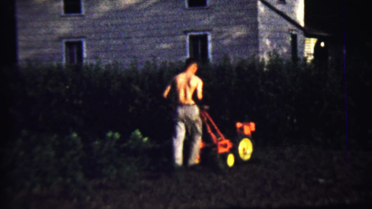 At the end of the clip, the man continues operating the small red tiller in the low-lit 1958 Kansas garden scene.