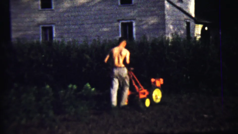 At the end of the clip, the man continues operating the small red tiller in the low-lit 1958 Kansas garden scene.