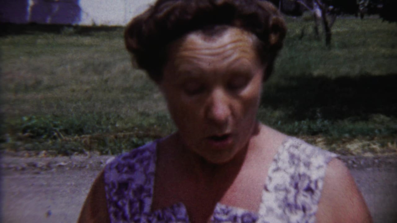 Adult woman in a patterned dress outdoors in Saint Francis, Kansas, in 1958 home-movie footage.