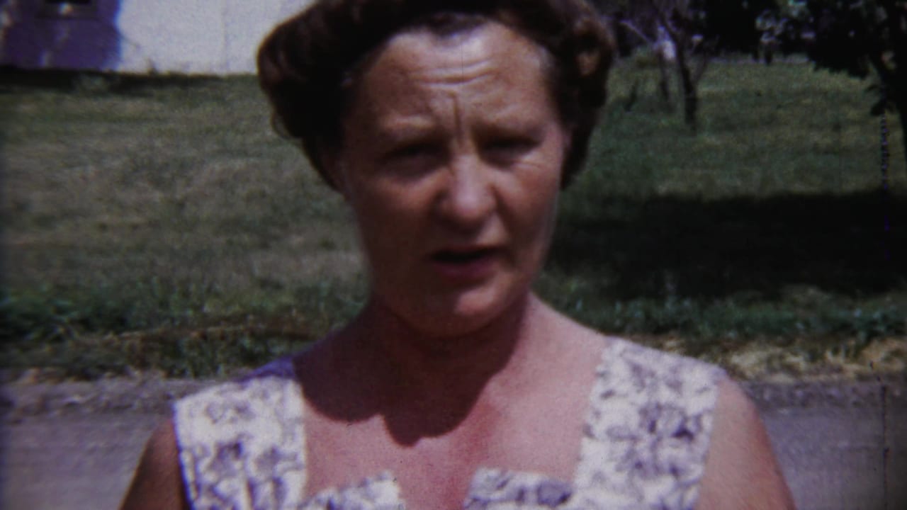 Woman facing the camera in a yard with grass and a house behind her.