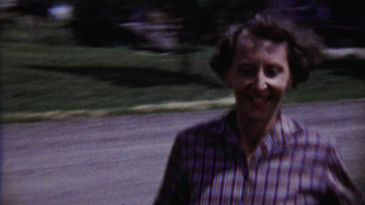 Young runner approaches the handheld camera in a 1958 Saint Francis, Kansas, residential yard scene.