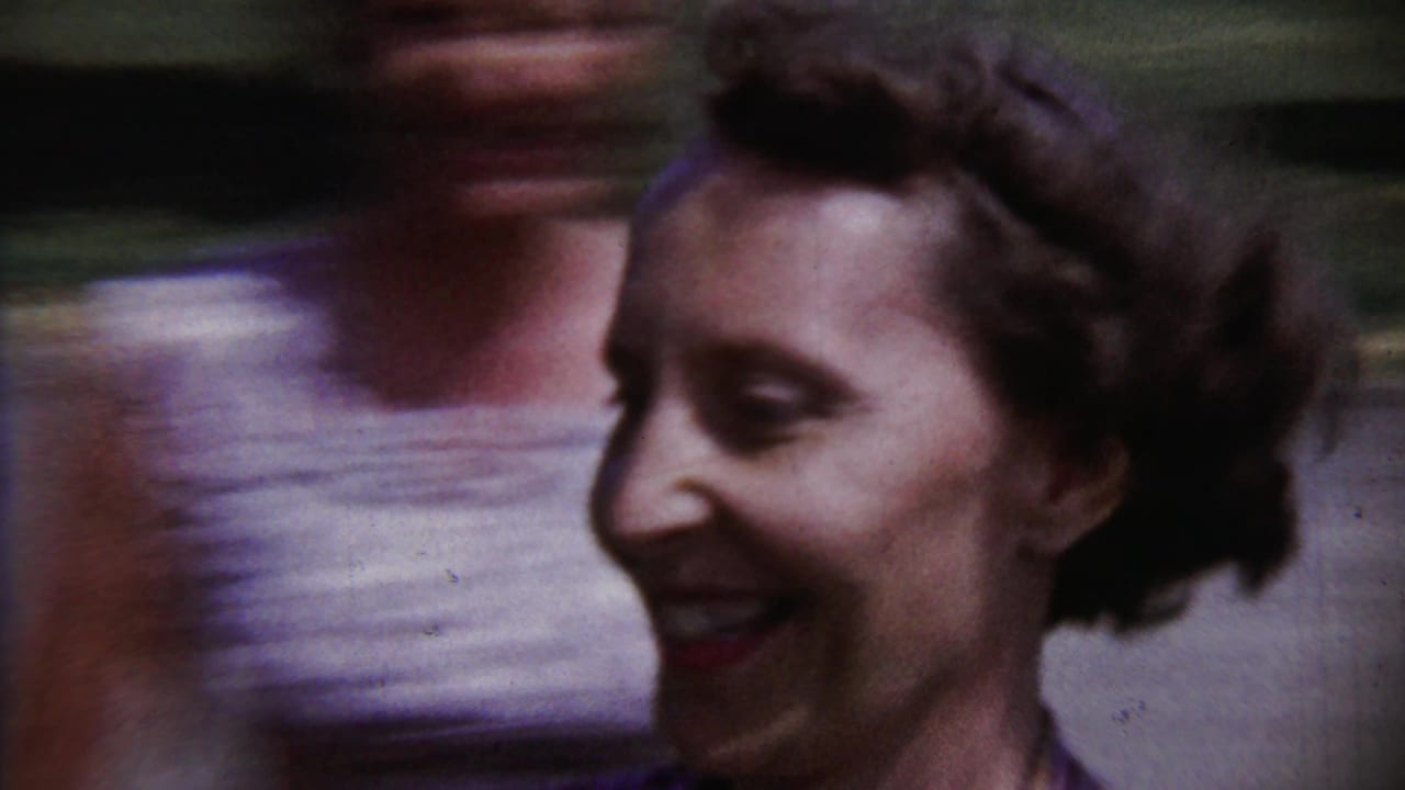 Blurred smiling face outdoors with another person partly visible behind her.