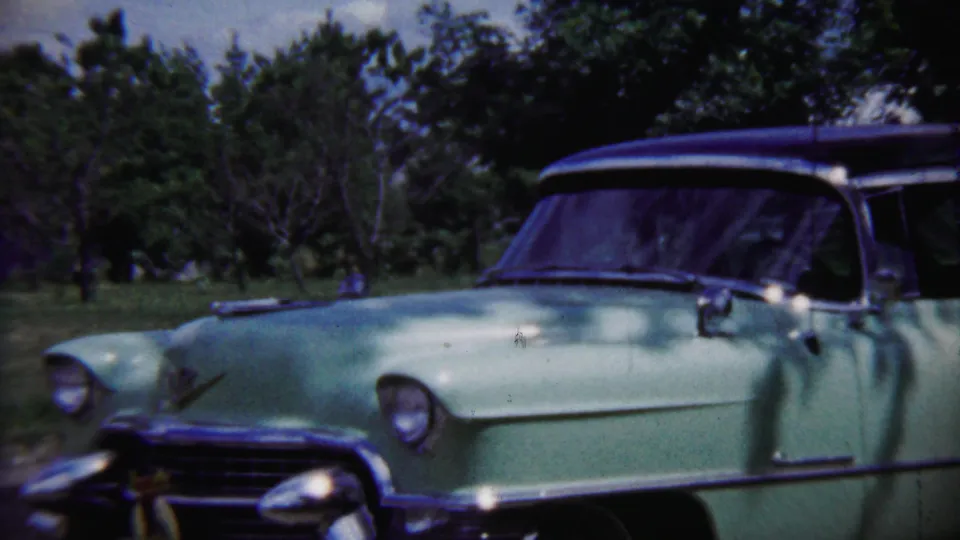 A light green mid-century car with chrome trim sits outdoors near trees in Saint Francis, Kansas, according to the clip metadata.