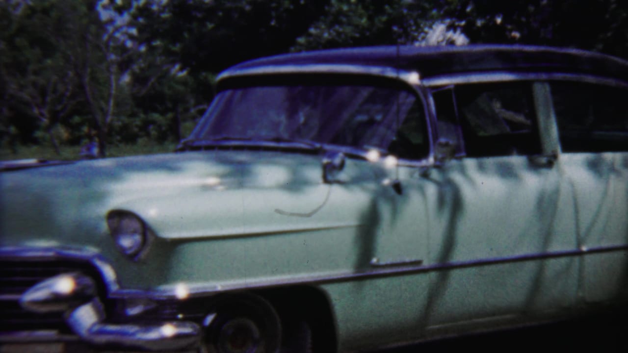 Closer side view of a pale green vintage sedan with chrome trim and shaded windows.
