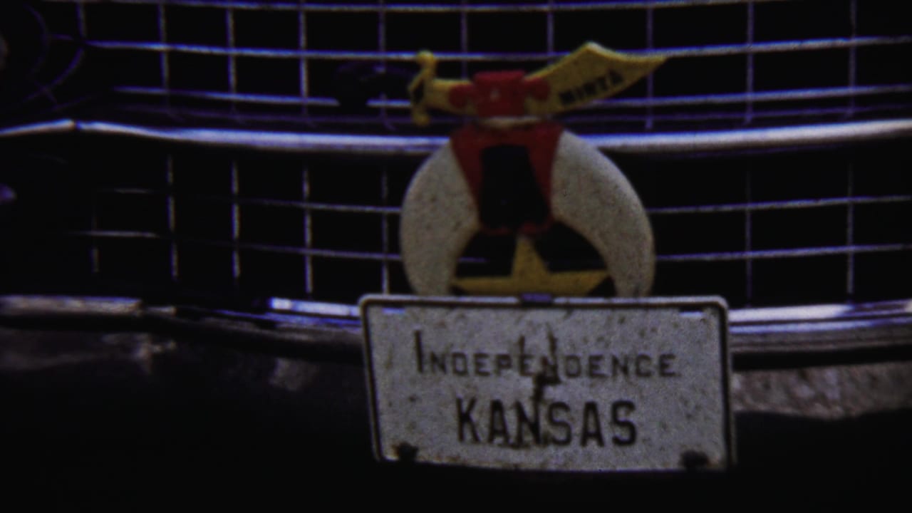 Close 1958 Kansas view of a classic car grille, chrome trim, hood ornament, and a readable plate marked Independence Kansas.
