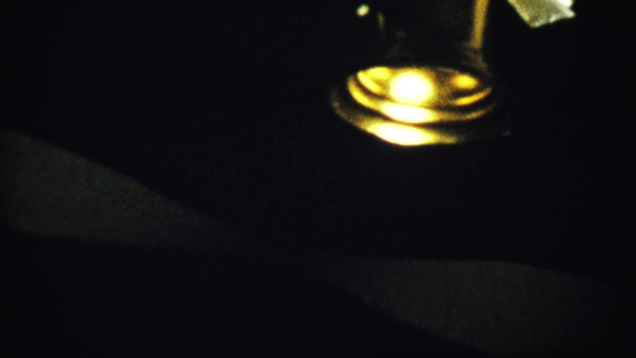 Dim spotlight and partial circular anniversary plaque in a dark scene.