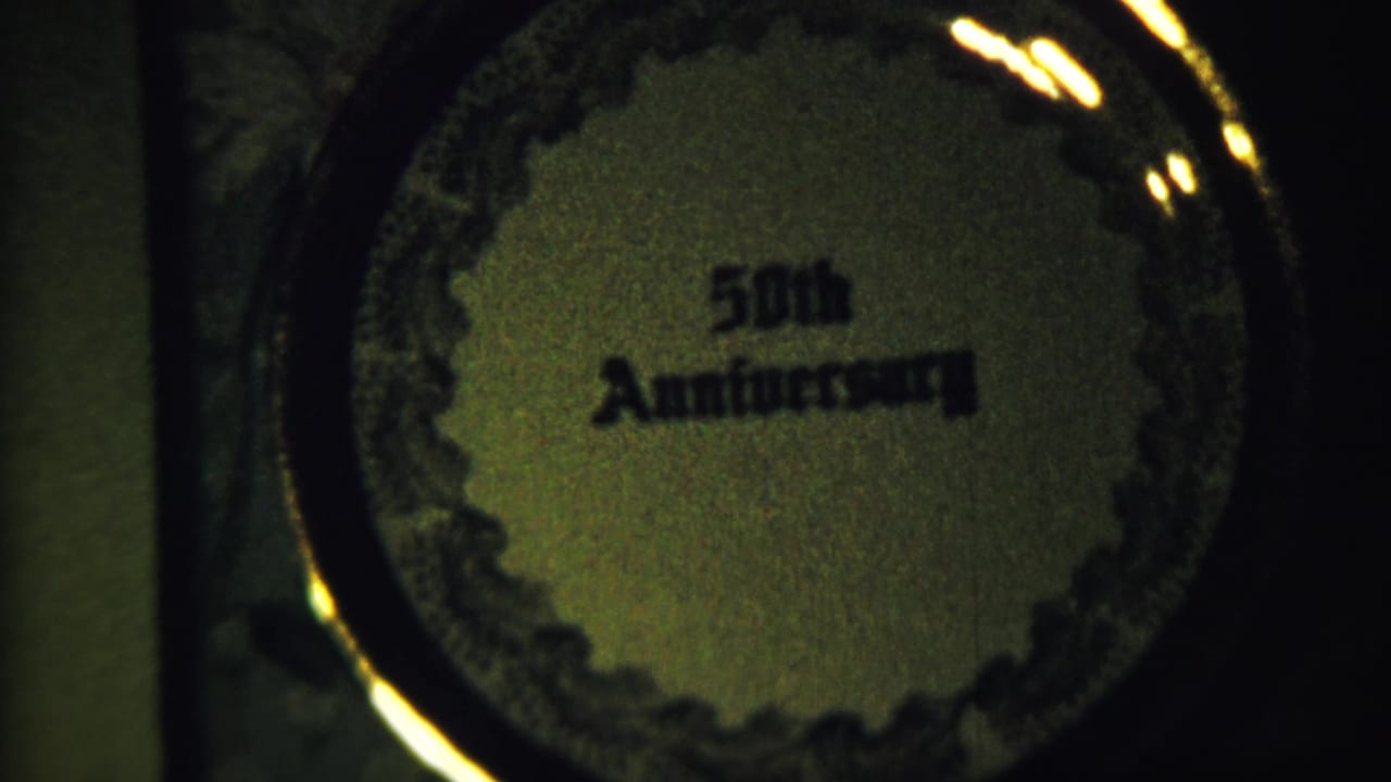 Close 8mm view of a circular 50th Anniversary plaque with decorative edging and warm reflections.