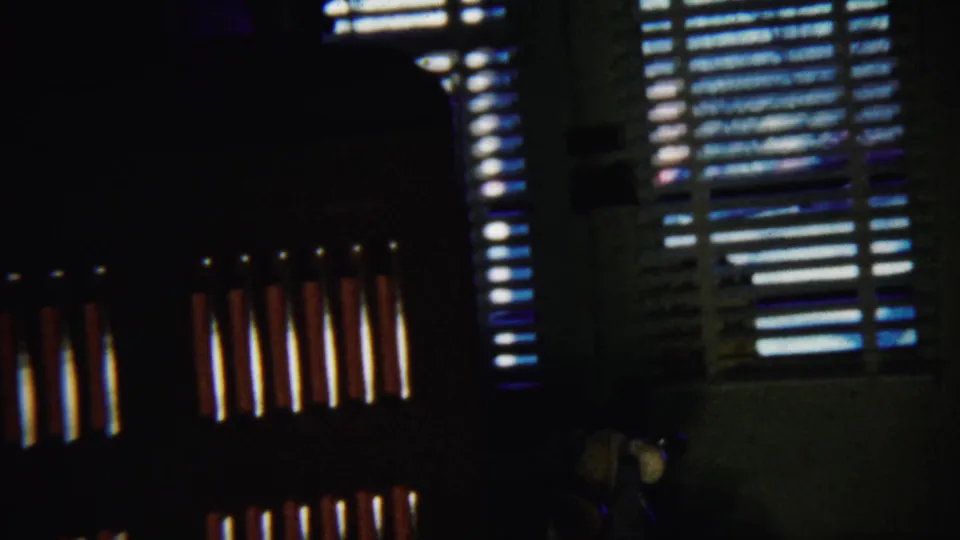 1958 Saint Francis, Kansas 8mm frame showing open blinds and striped daylight across a dim interior wall.