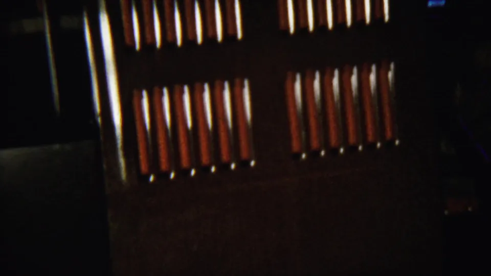 Low-light 1958 home-movie frame with bright blind slats and a dark interior wall or cabinet surface.