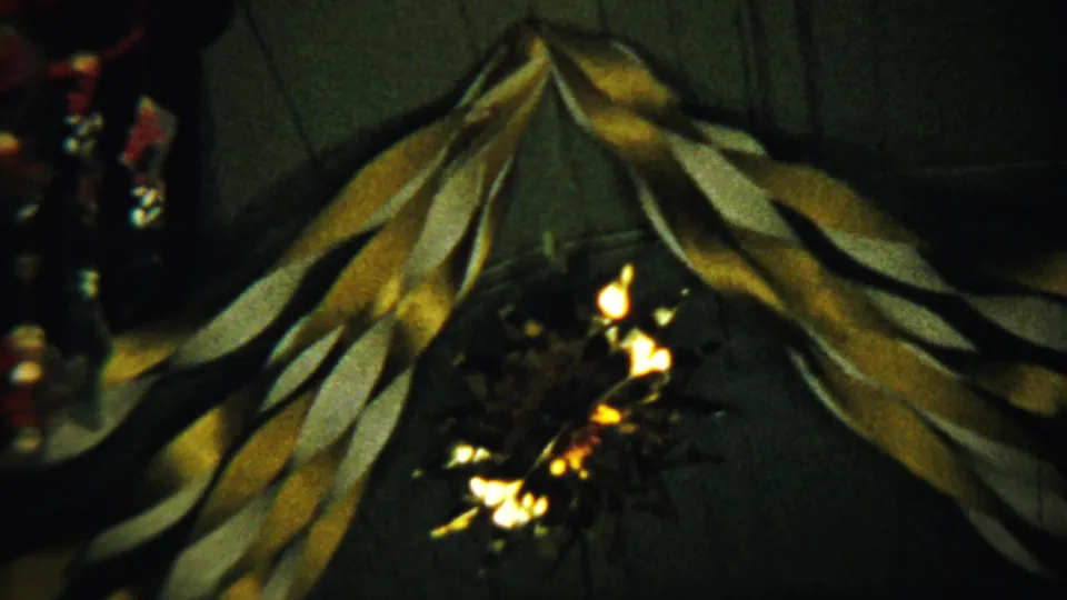 1958 Kansas home-movie frame with ribbon-like drapery and small glowing lights against a dim interior background.