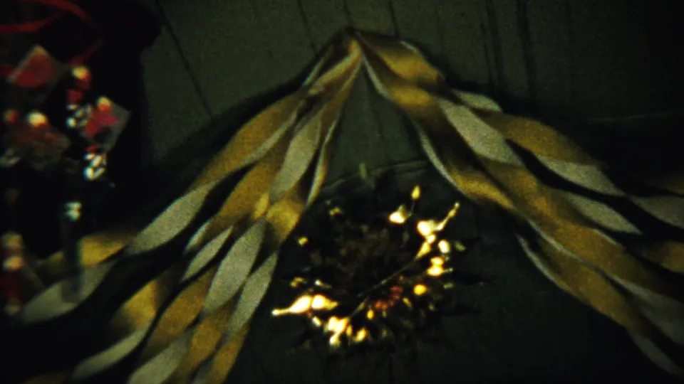 1958 Saint Francis, Kansas home-movie still showing draped yellow and white streamers, a dark background, and a glowing center light.