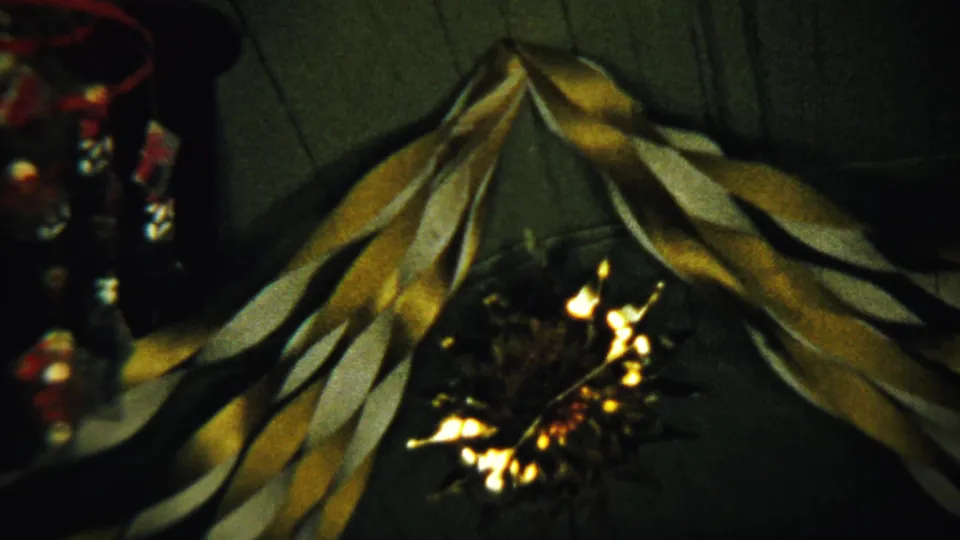 Close 8mm view of gold and white holiday streamers on a ceiling in the 1958 Saint Francis, Kansas home-movie clip.