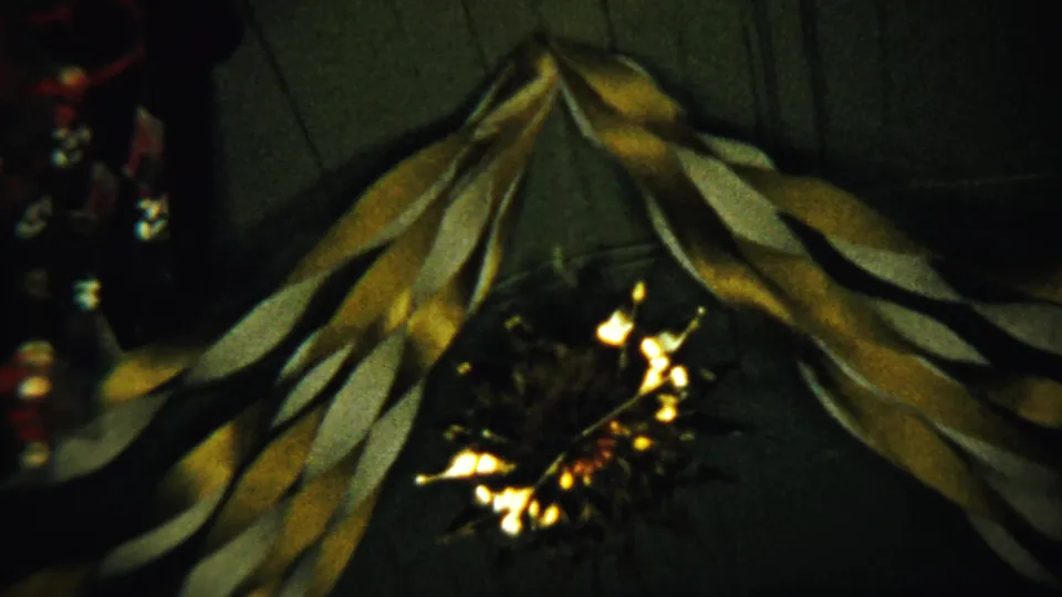 1958 8mm home-movie frame from Saint Francis, Kansas showing draped holiday ribbons and low-light interior reflections.