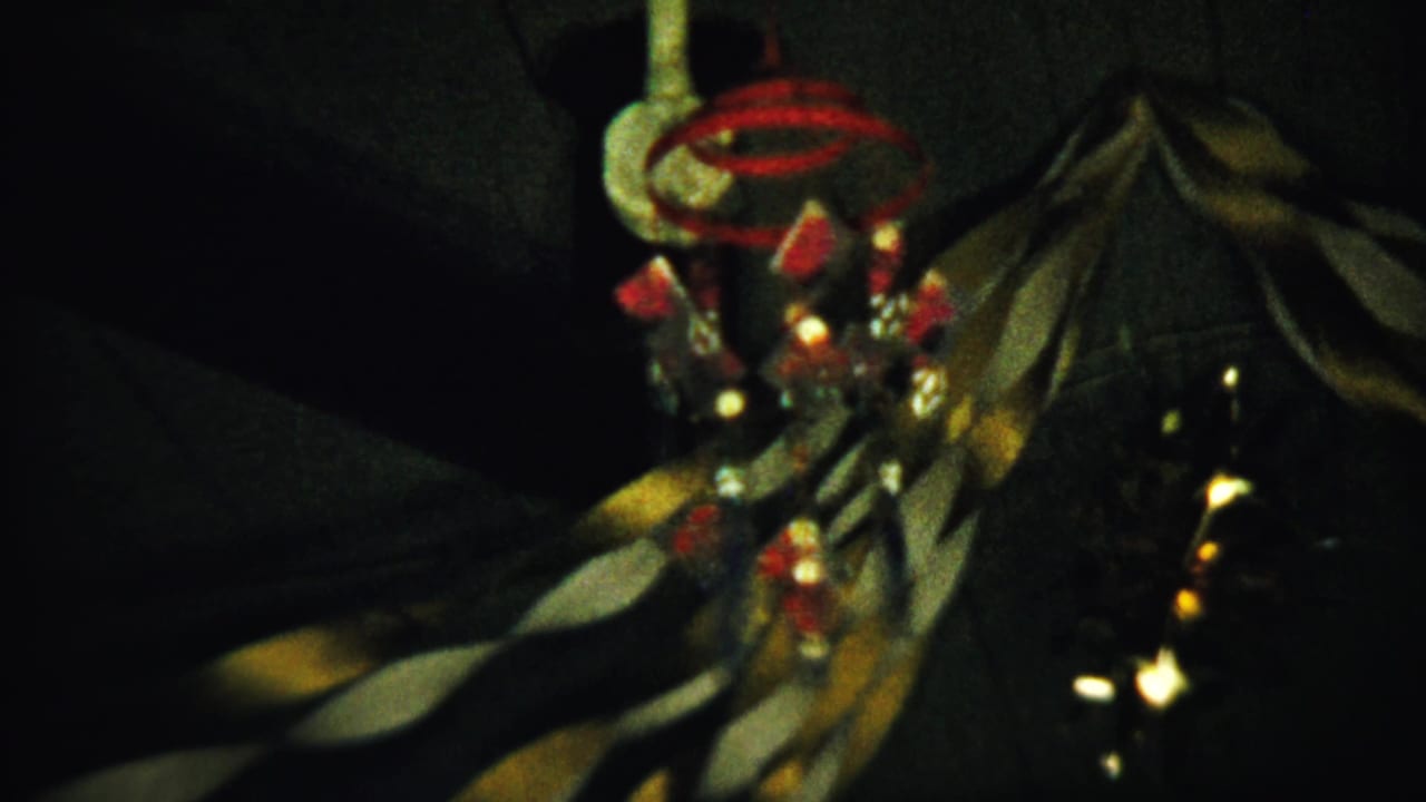 Dim close-up of a hanging red and white ornament beside dark draped fabric.