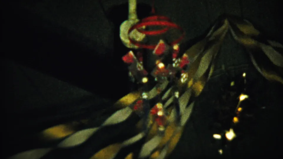1958 Saint Francis, Kansas 8mm frame showing a hanging ornament with red and white elements in a shadowed interior.