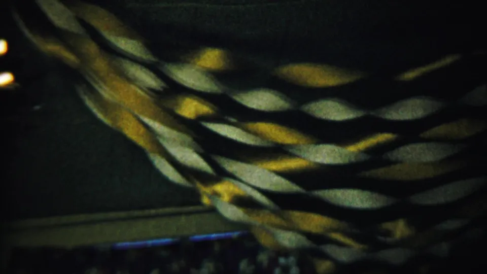 1958 Saint Francis, Kansas home-movie view of twisted paper garland crossing a dim interior wall, with darker room details below.