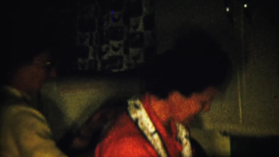1958 Saint Francis, Kansas frame showing a person in a red shirt beside Christmas decorations inside a private home interior.