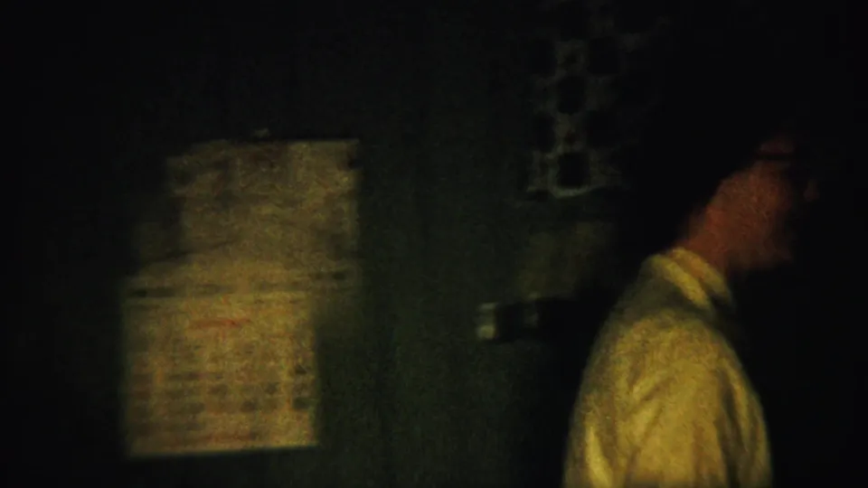 A dark 1958 Saint Francis, Kansas kitchen frame shows a person in profile beside patterned curtains and household items.