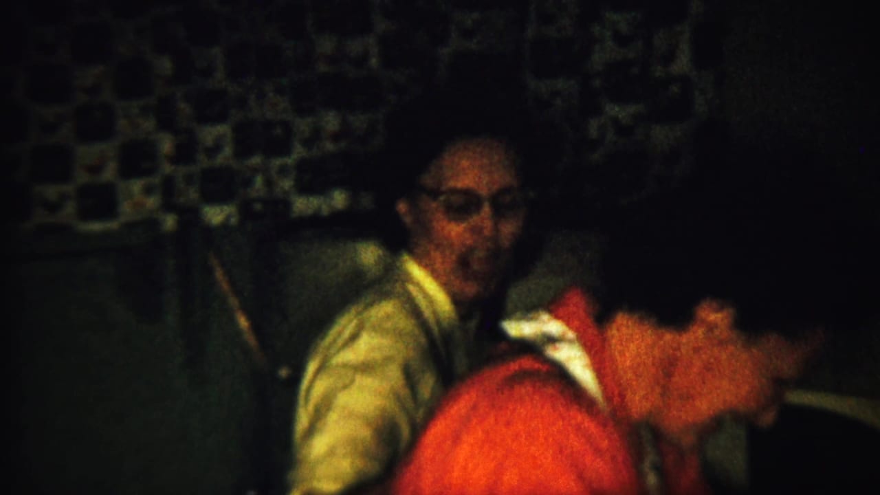 Dim kitchen scene with a man in glasses and a person in a red shirt nearby.