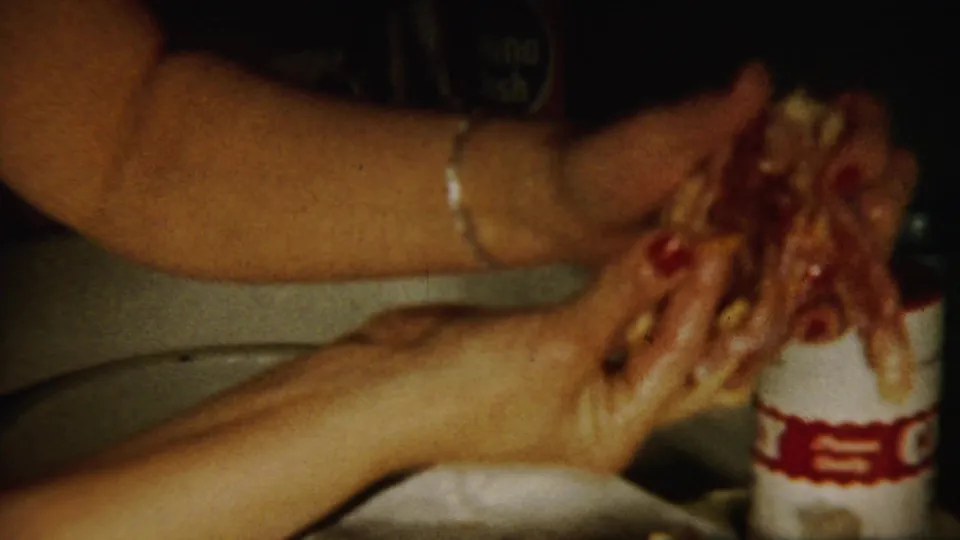 A close 1958 home-movie view shows hands working with food near a white labeled container on the kitchen counter.