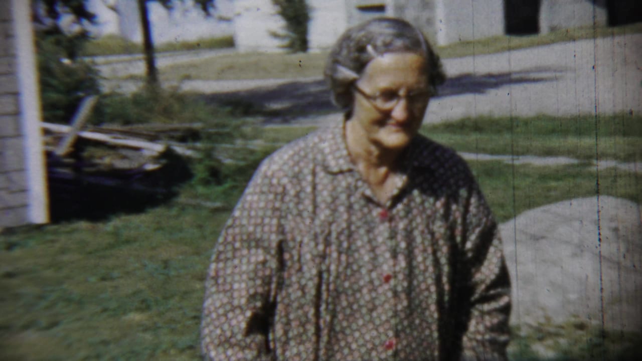The woman turns from the camera and begins walking across the lawn in the 1959 Chadron, Nebraska home-movie scene.