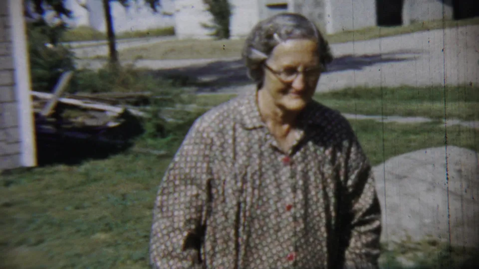 The woman turns from the camera and begins walking across the lawn in the 1959 Chadron, Nebraska home-movie scene.