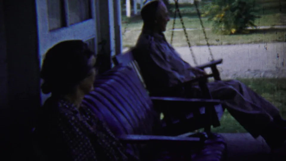 The porch view continues with an older couple seated in shade, the man in profile and the woman in the foreground.