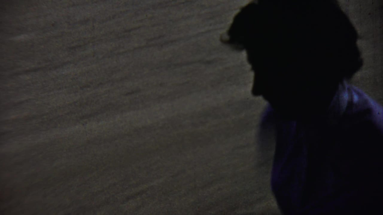 Dark partial foreground figure near a parked classic car on a rural roadside.