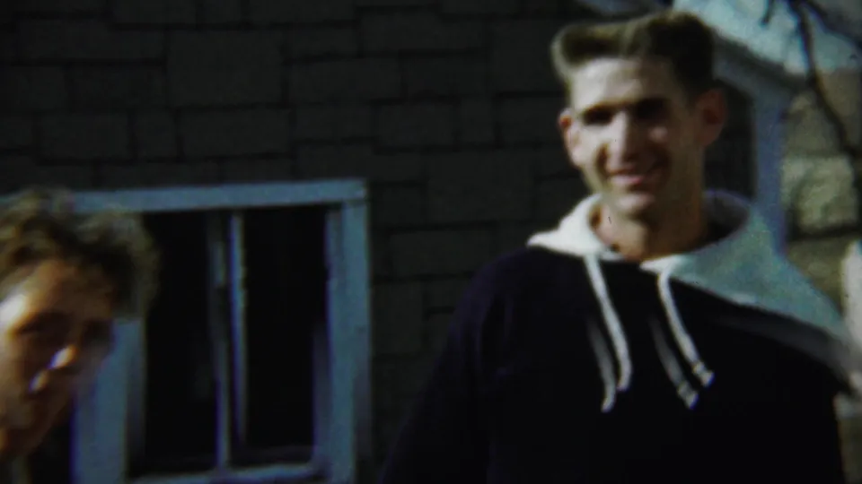 A handheld 1959 Chadron, Nebraska frame shows two young men and a young woman near a brick house, with one figure partly cropped at left.