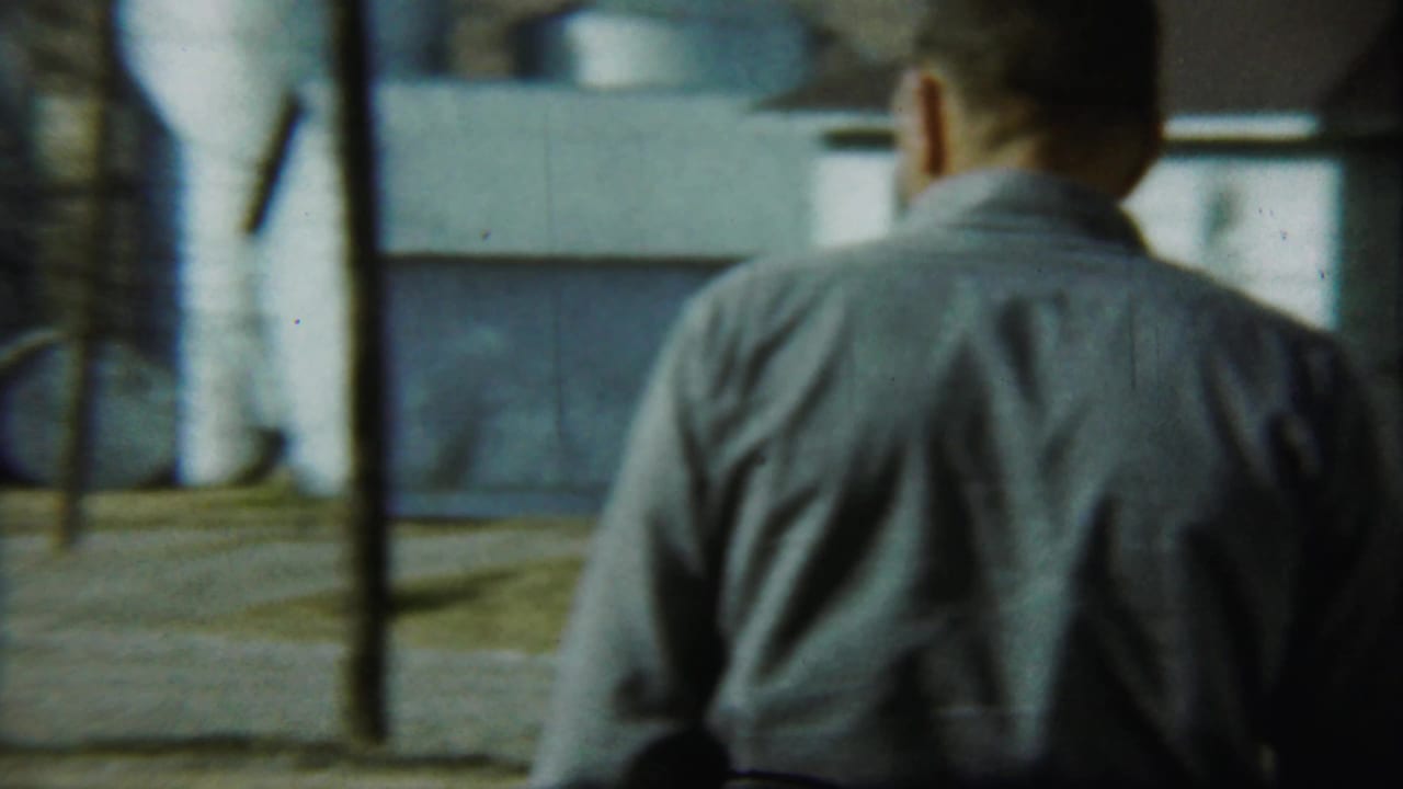 Man seen from behind facing an adult couple outside a shingled house.