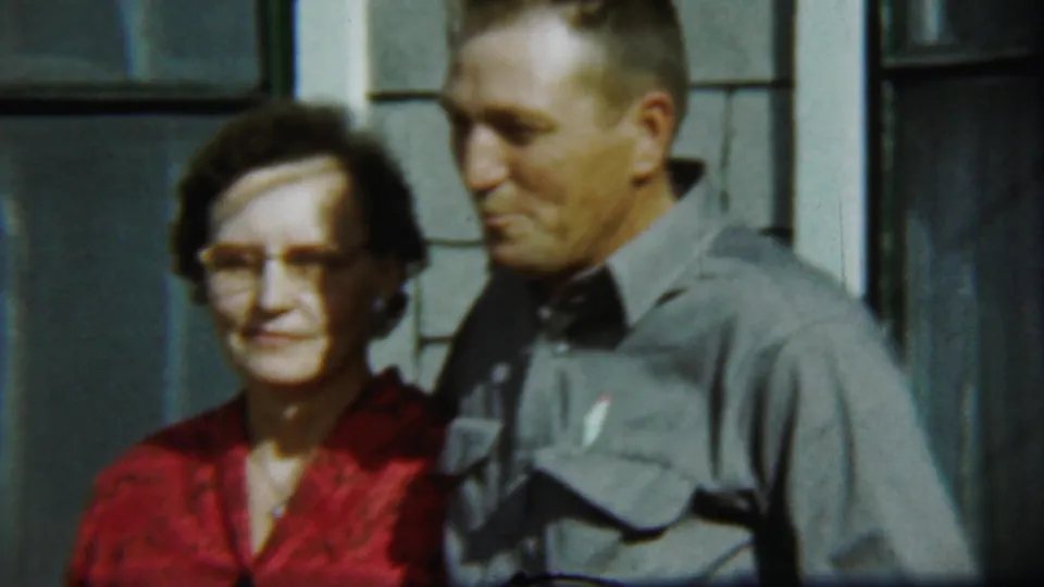 In this 1959 home-movie frame, the woman looks toward the camera as the man turns slightly downward with a smile.