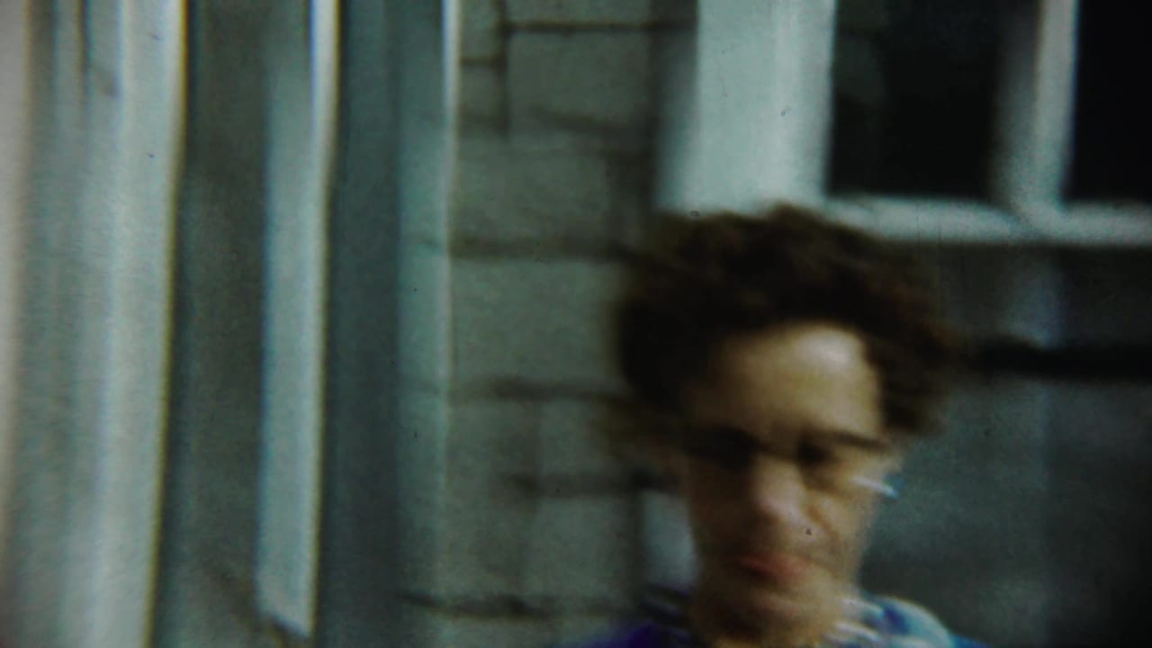 Woman in glasses moving past house windows and siding.