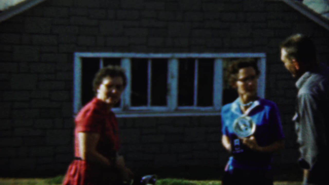 Two women with flash cameras and a man stand outside a building.