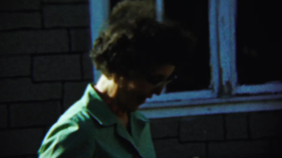 The woman turns in profile outside the Chadron brick building, her glasses and green shirt visible in low light.