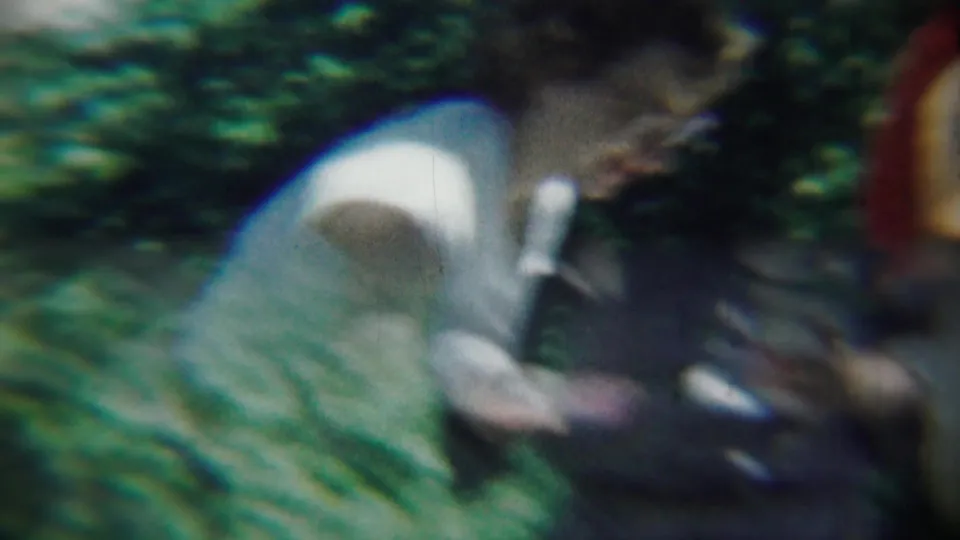 The woman appears close to a patterned lawn chair, with garden plants and soft 8mm motion blur around her.