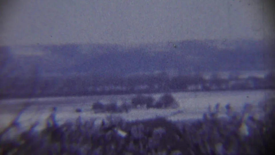 1959 Chadron, Nebraska frame showing dark winter brush, open snow-covered ground, and distant hills through a soft 8mm scan.