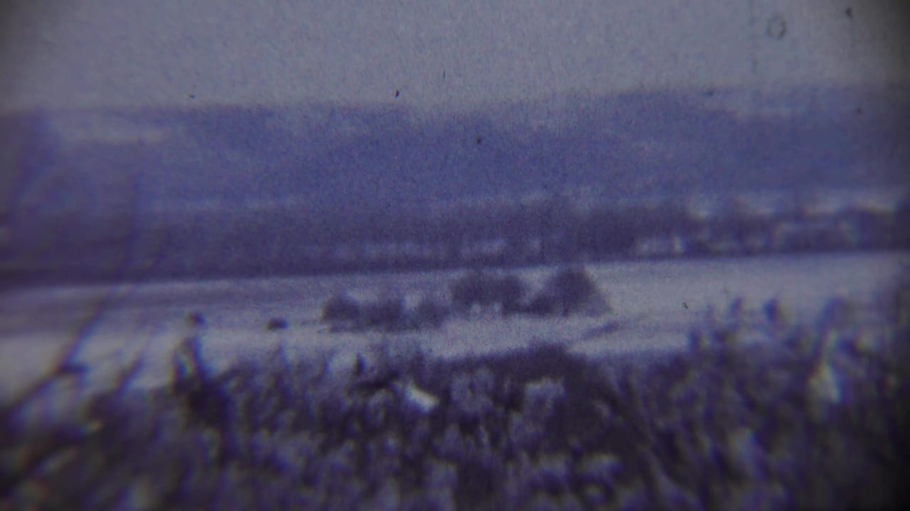Soft 8mm view of a snowy Chadron-area landscape with distant hills and a small dark airborne object, likely from a 1959 home movie.