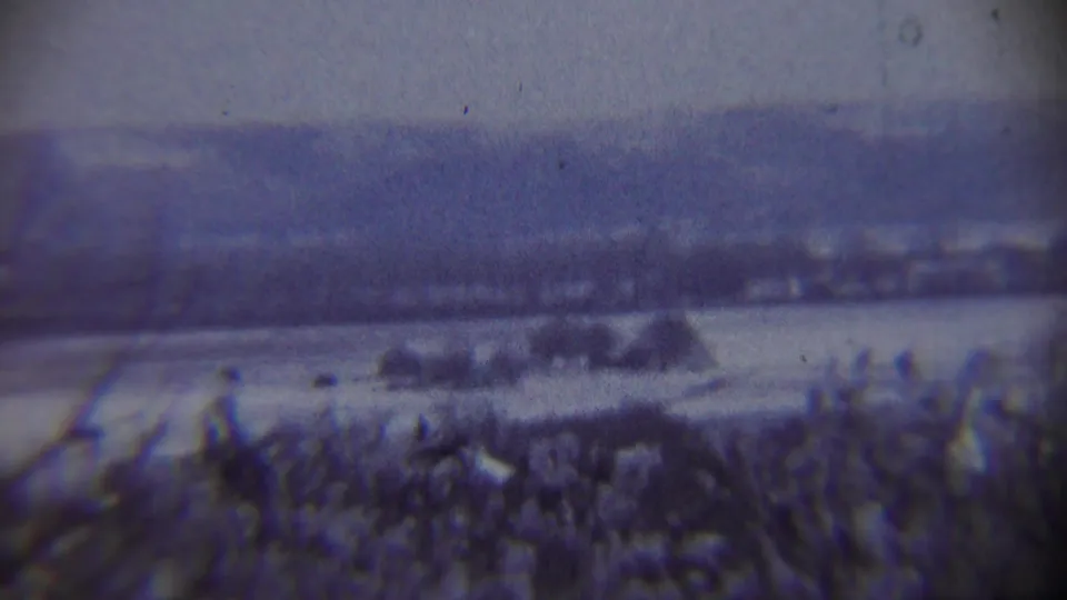 Soft 8mm view of a snowy Chadron-area landscape with distant hills and a small dark airborne object, likely from a 1959 home movie.