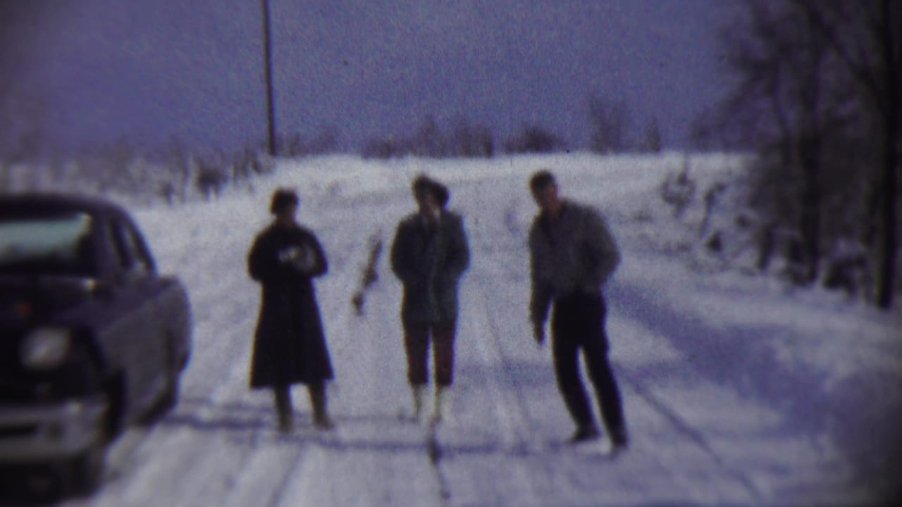 Three people in winter clothing stand on a snowy rural road in Chadron, Nebraska, with a car partly visible at left.